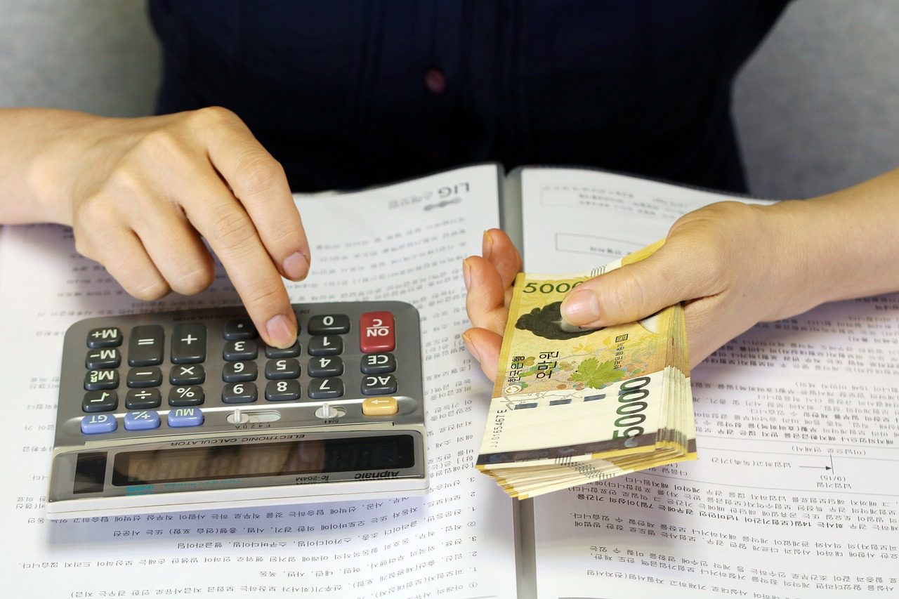 계산기와 지폐로 가계부를 정리하는 사람의 손