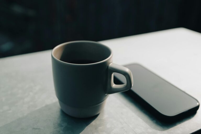 오후 햇살 속 노션 워크스페이스와 도자기 커피잔이 보인다