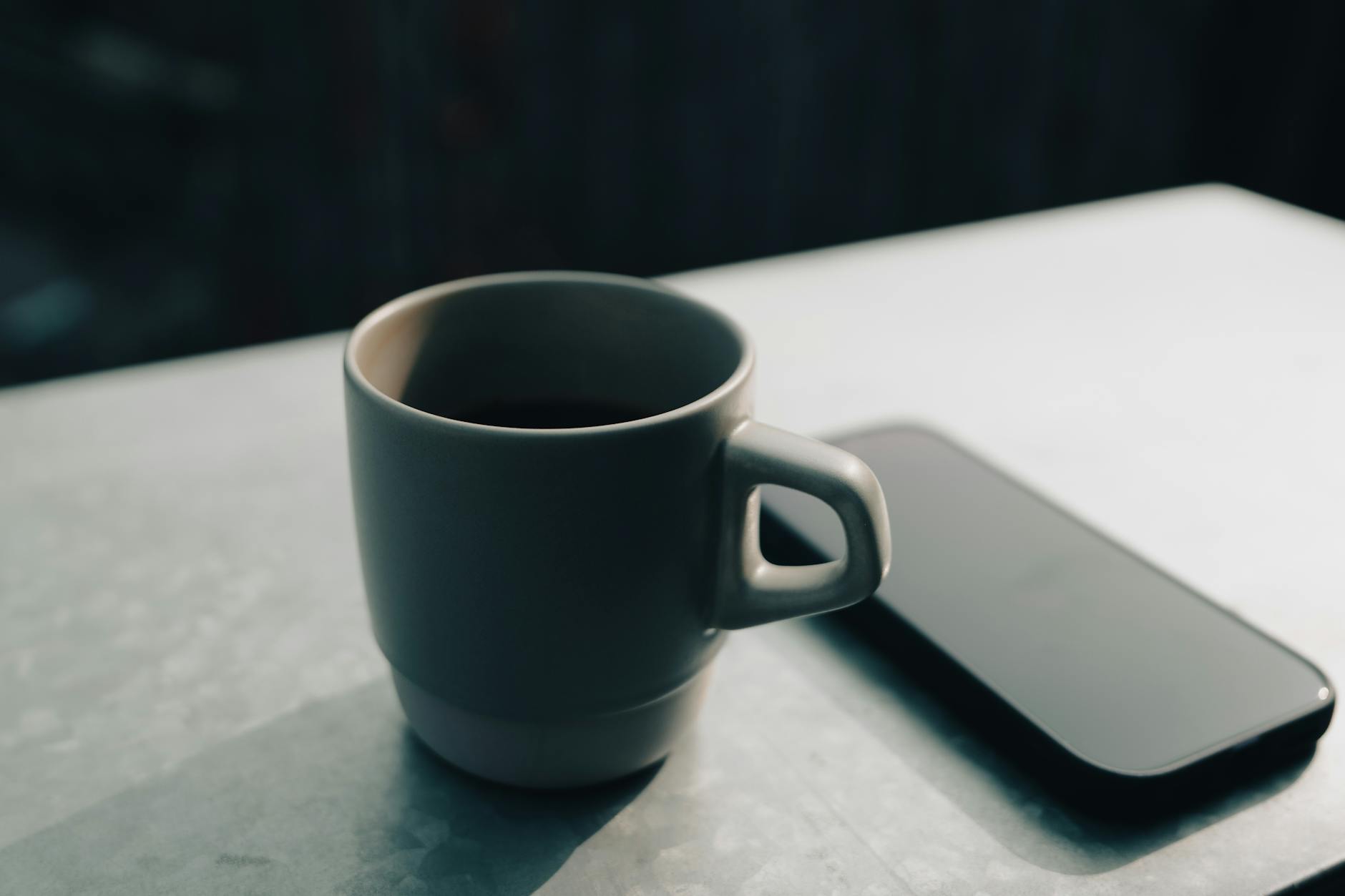 오후 햇살 속 노션 워크스페이스와 도자기 커피잔이 보인다